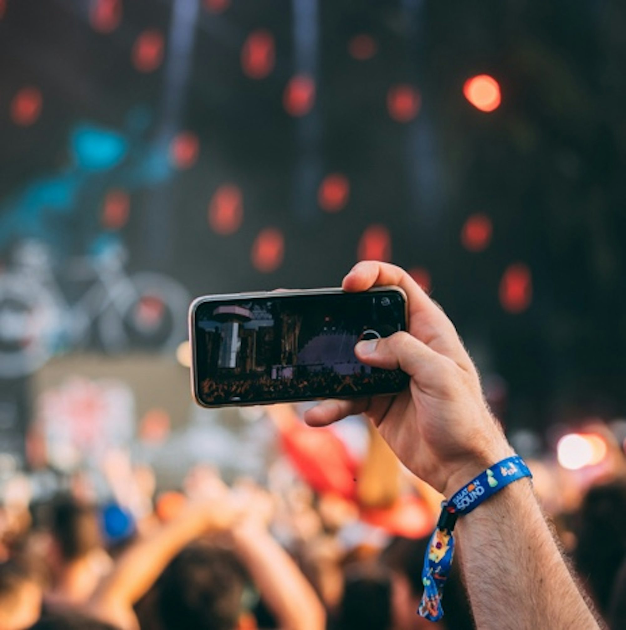 Person taking a landscape photo with their smartphone at a concert