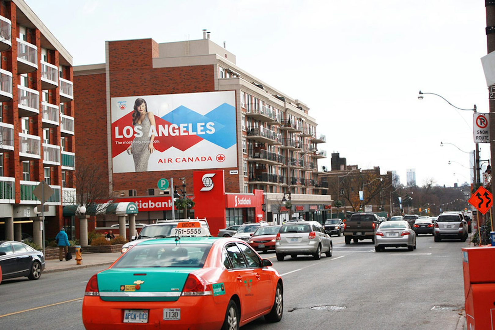 Panneau d'affichage grand format d'Astral sur le côté d'un immeuble le long d'une rue passante, mettant en vedette une publicité de Air Canada