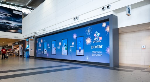 Large digital Astral board on a wall inside Ottawa's airport featuring a Porter ad