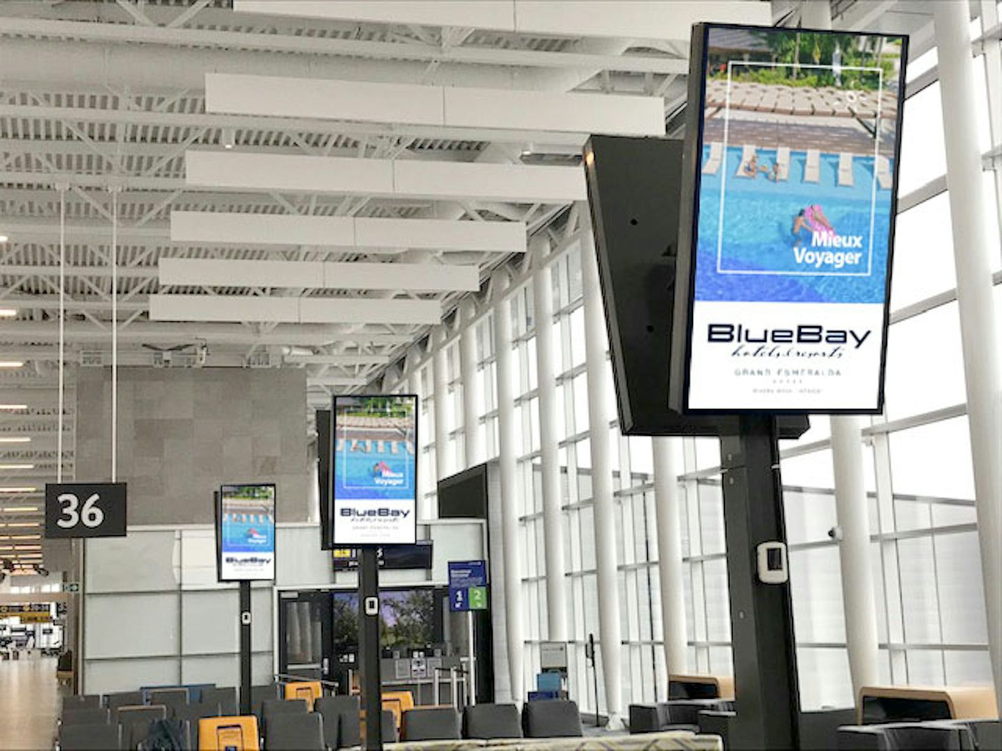Digital Astral boards above a gate at Quebec's Jean-Lesage airport, featuring a BlueBay ad