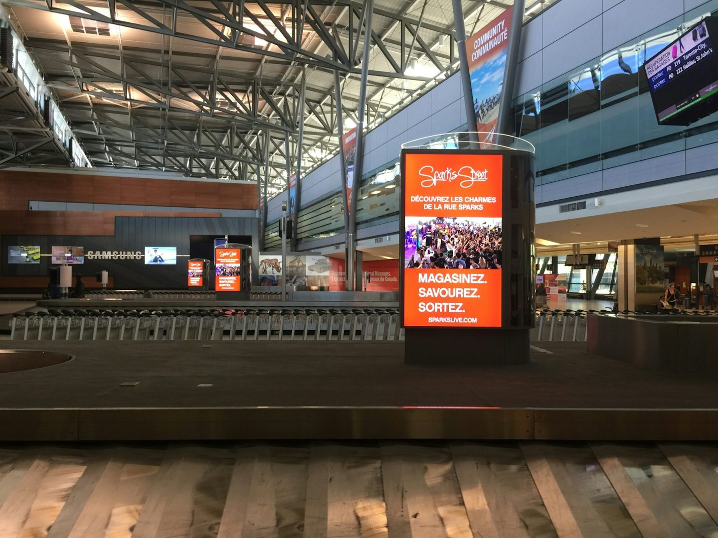 Digital Astral board featuring a Sparks Street ad at a baggage carousel at Ottawa's airport