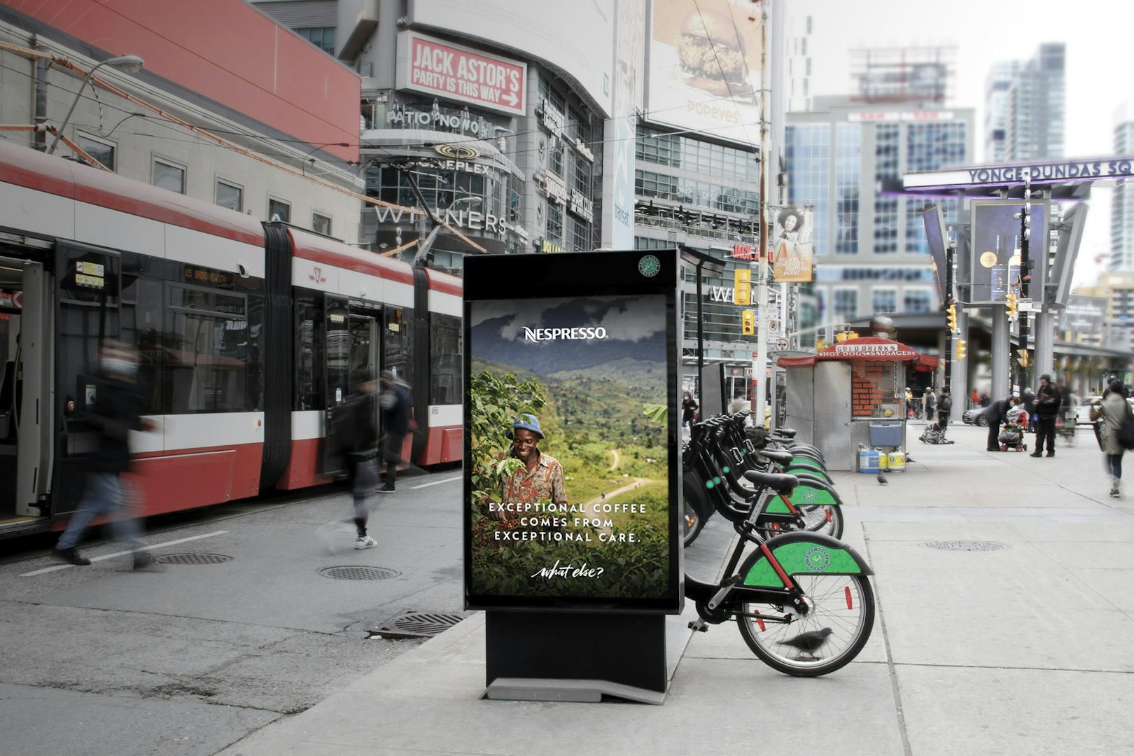 Astral board attached to a Bikeshare station, featuring a Nespresso ad, in Yonge-Dundas Square