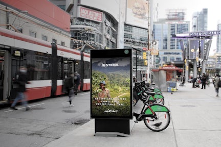 Panneau astral attaché à une station de vélos en libre-service, avec une publicité Nespresso, à Yonge-Dundas Square