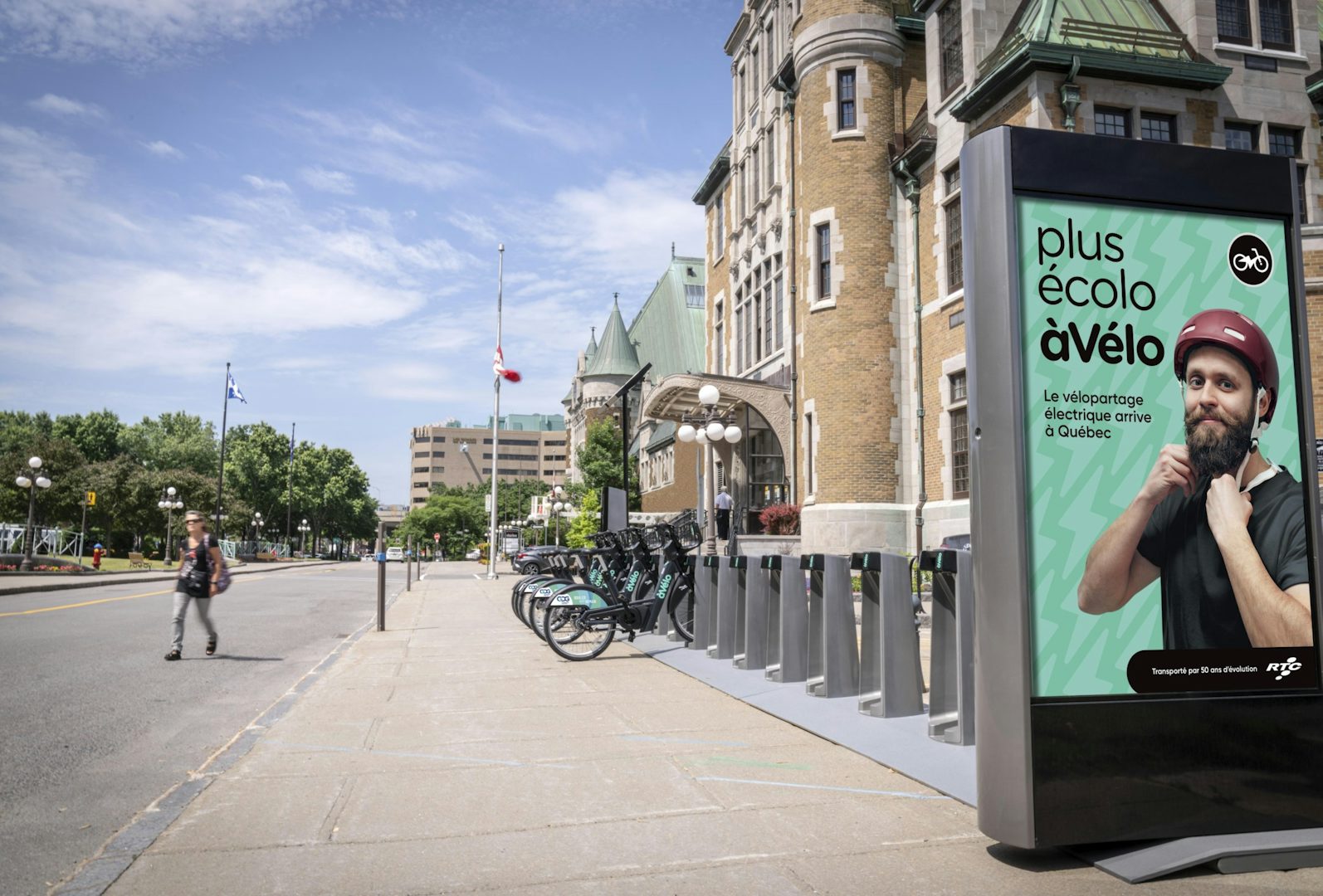 Astral board attached to a Bikeshare station, featuring an RTC ad, beside a government building