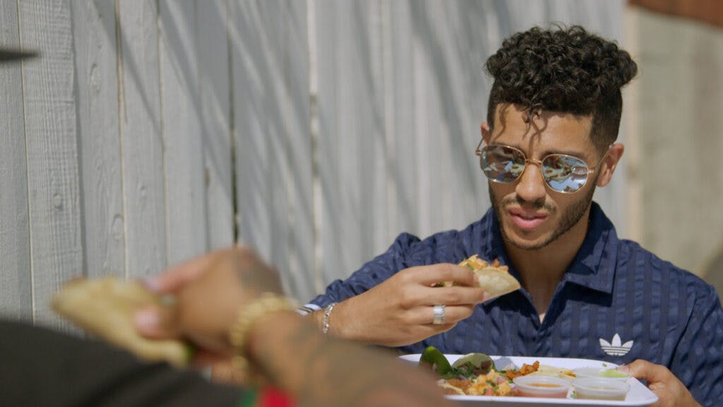 Mena Massoud eats a vegan taco in the series premiere of EVOLVING VEGAN