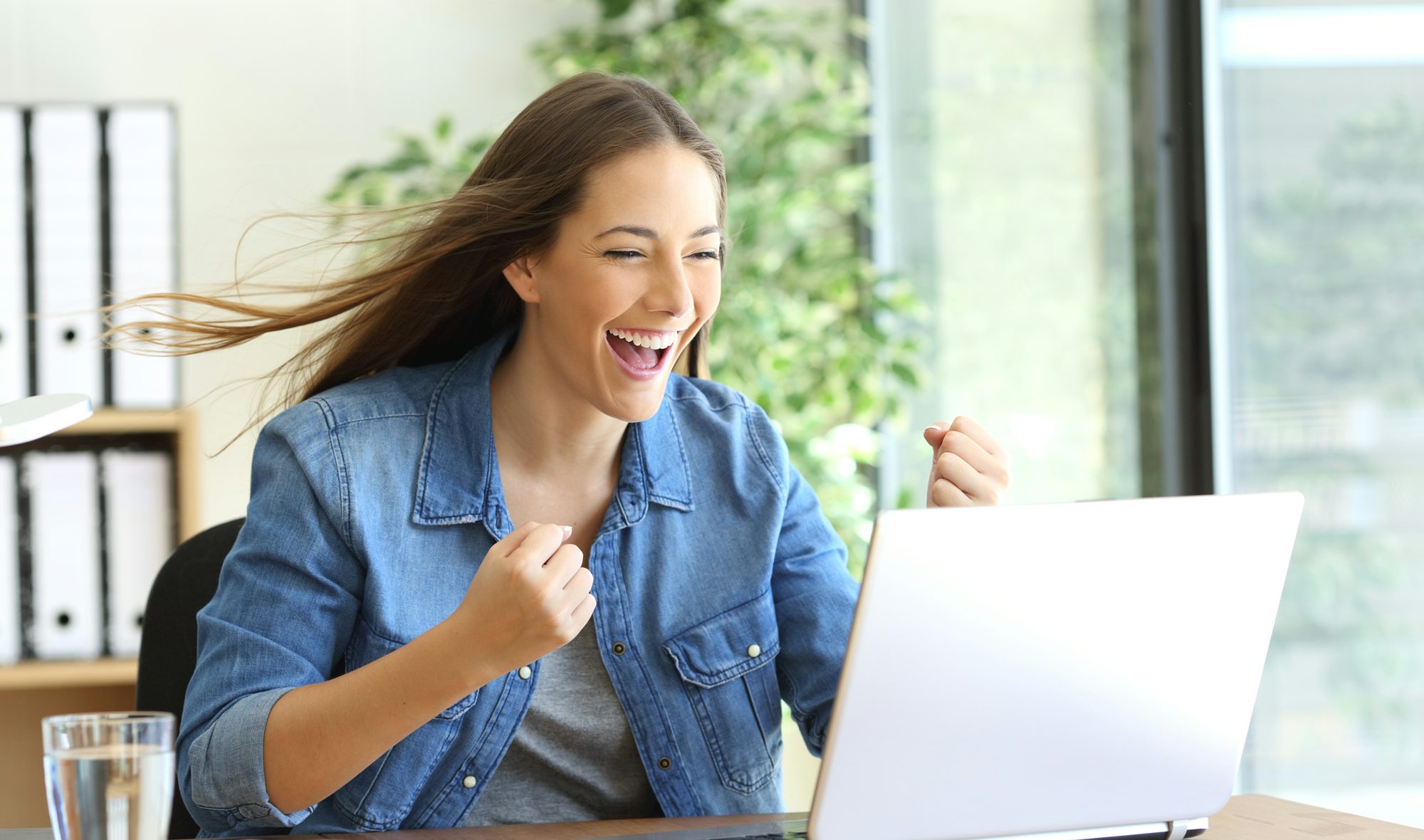 Excited lady looking at her computer. She seems to be celebrating a win!