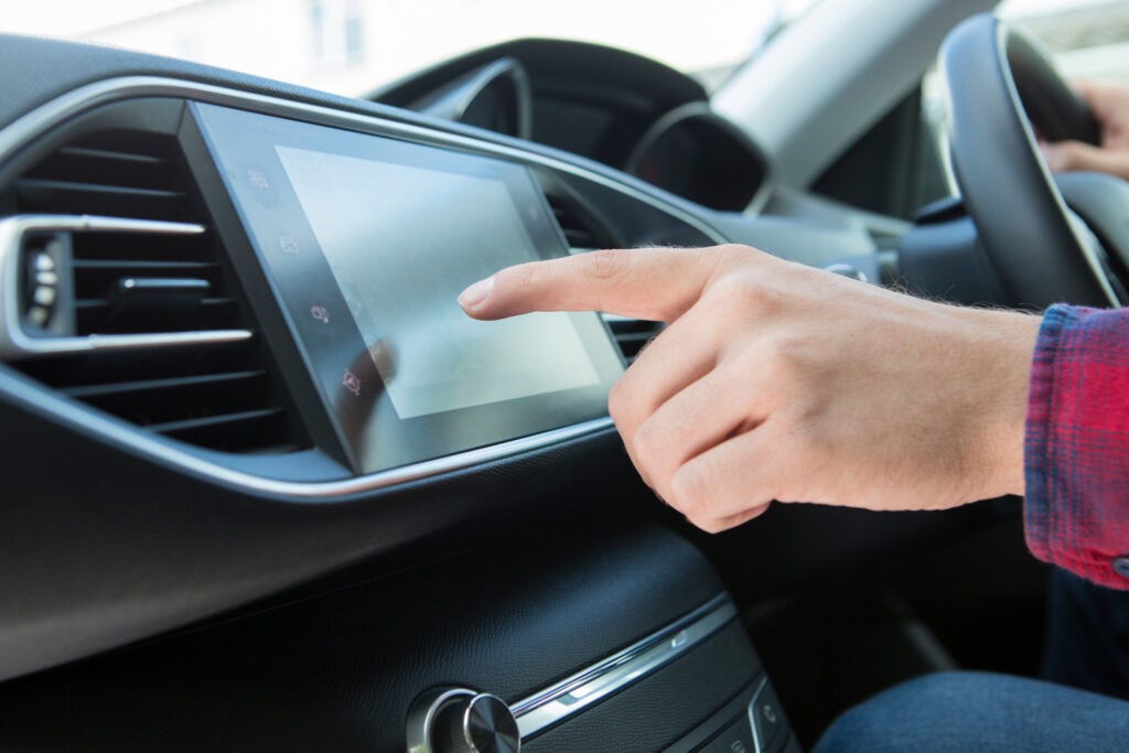 Close Up Of Driver Using Touchscreen In Car