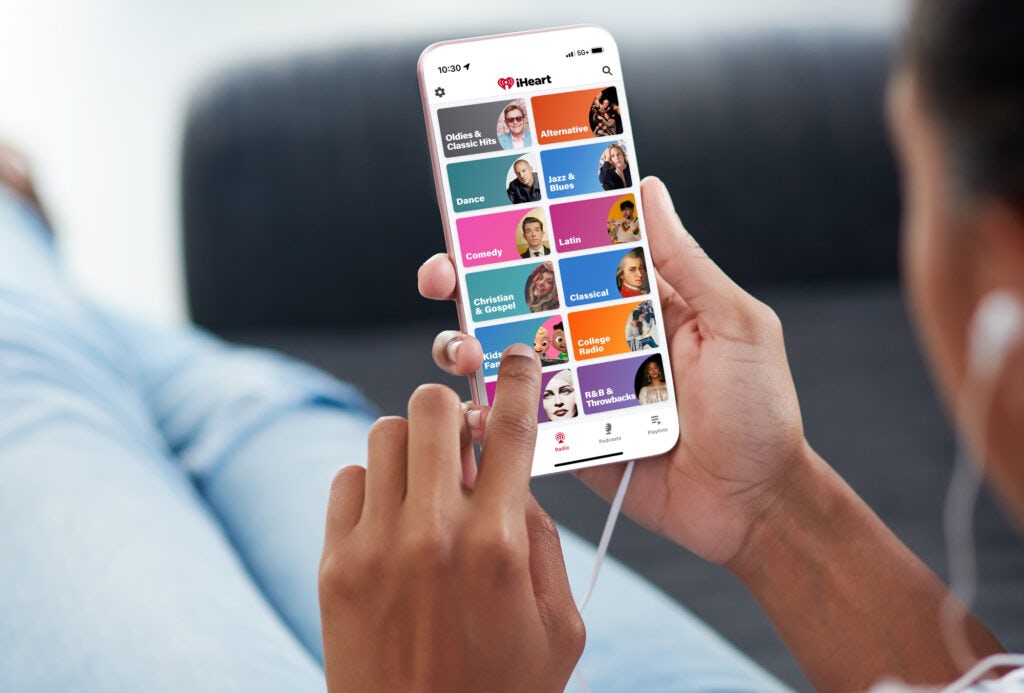 Black women holding phone with the iheartradio app