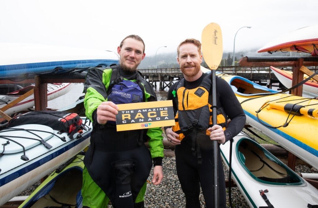 Jon Montgomery in British Columbia in front of kayaks holding a paddle from The Amazing Race Canada