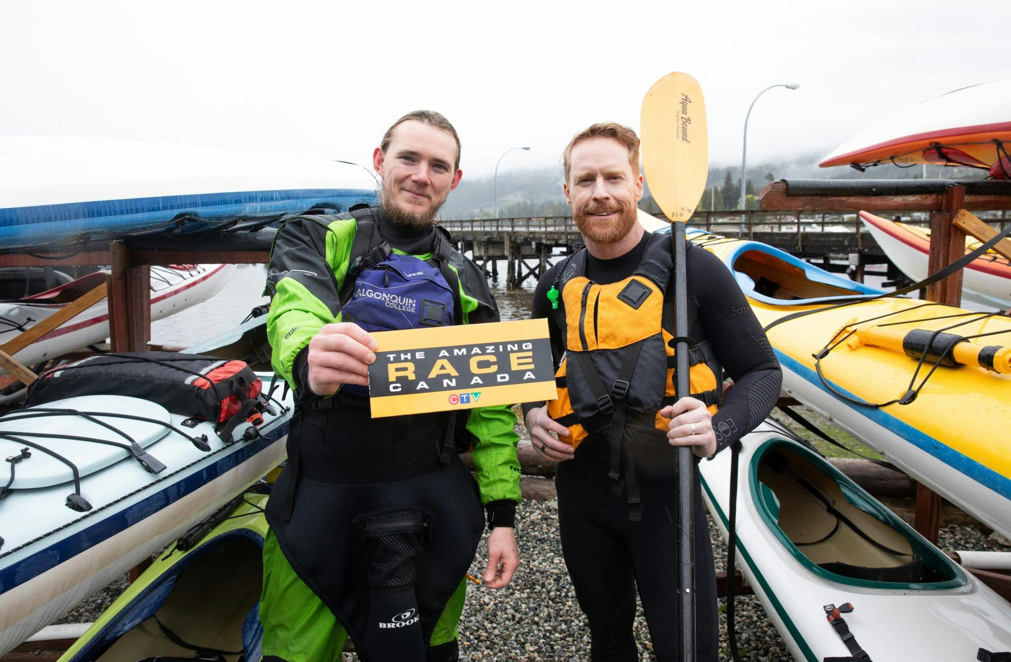 Jon Montgomery in British Columbia in front of kayaks holding a paddle from The Amazing Race Canada