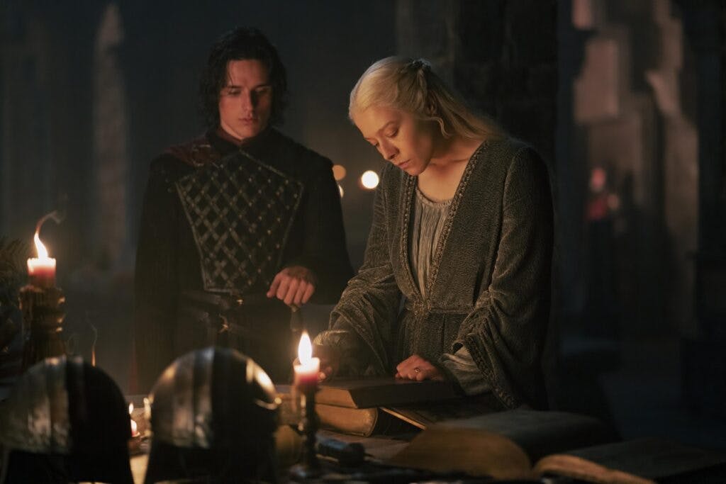 Prince Jacaerys Velaryon and Queen Rhaenyra Targaryen speaking in front of candles and reading a history book about ancient valyria and Targaryen history