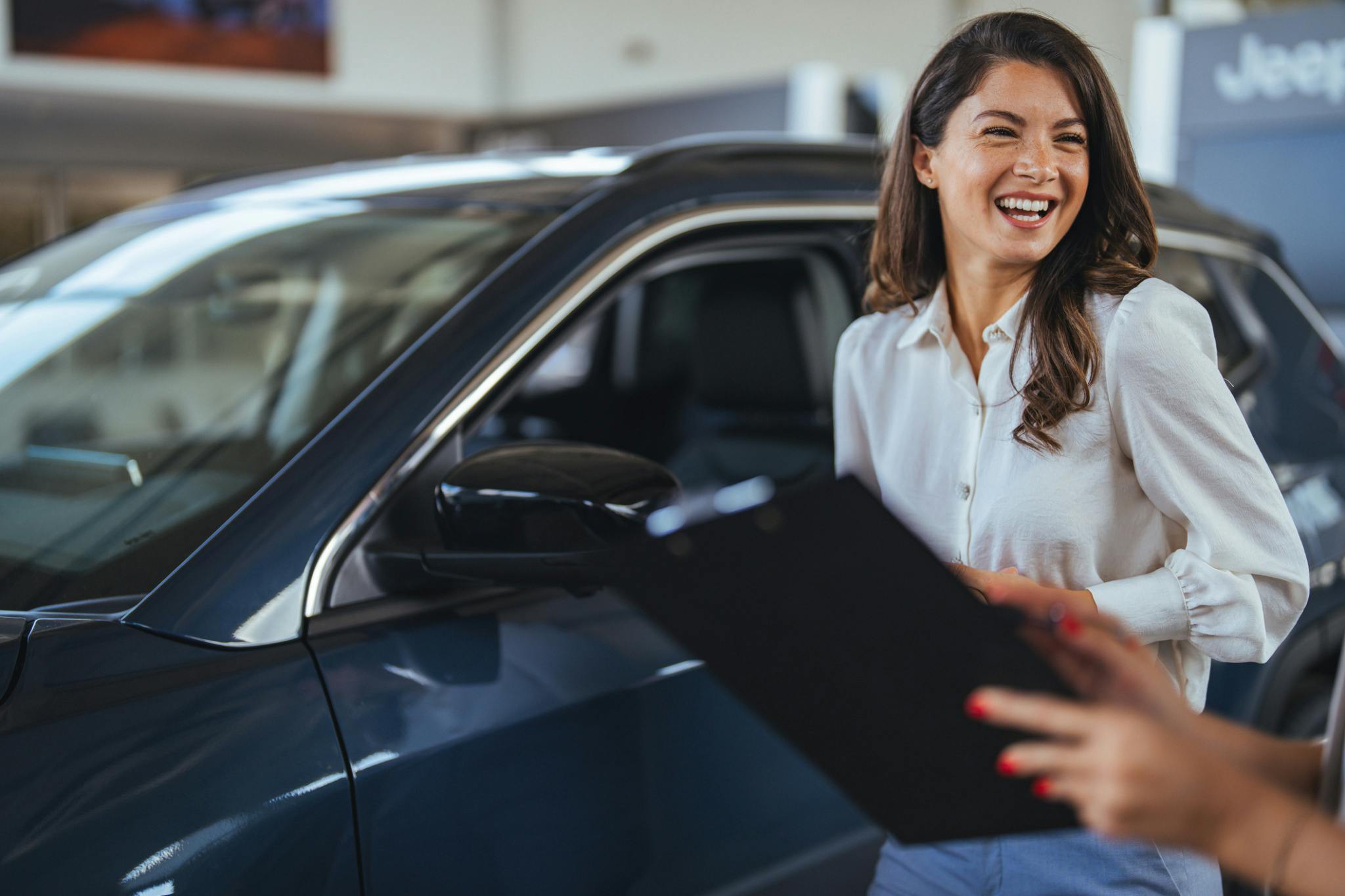 Woman looking happy beside a luxury car